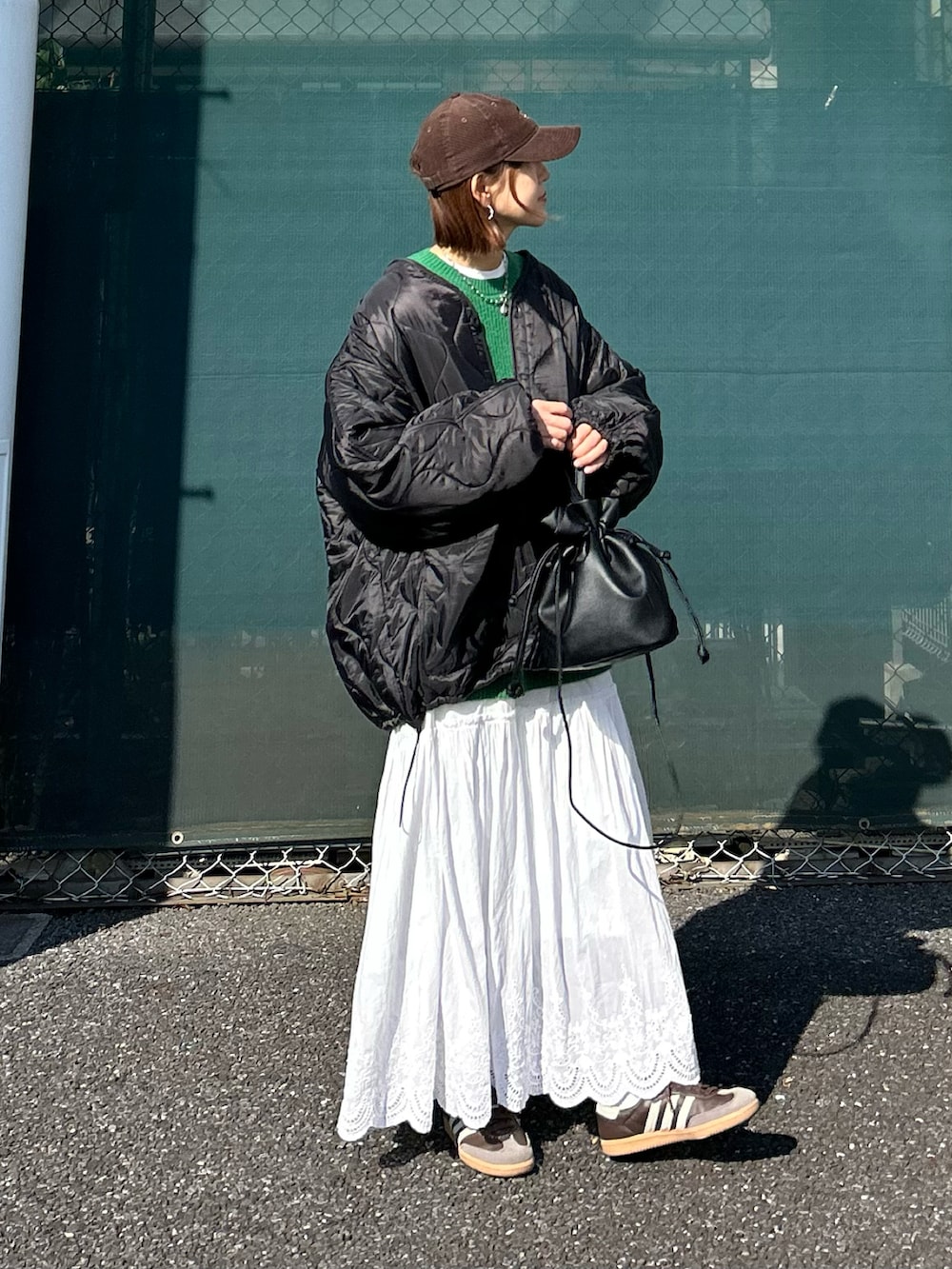 ブラック系のブルゾン、グリーン系のニット/セーター、ホワイト系のスカートを着用したレディースの冬コーディネートの2枚目の写真