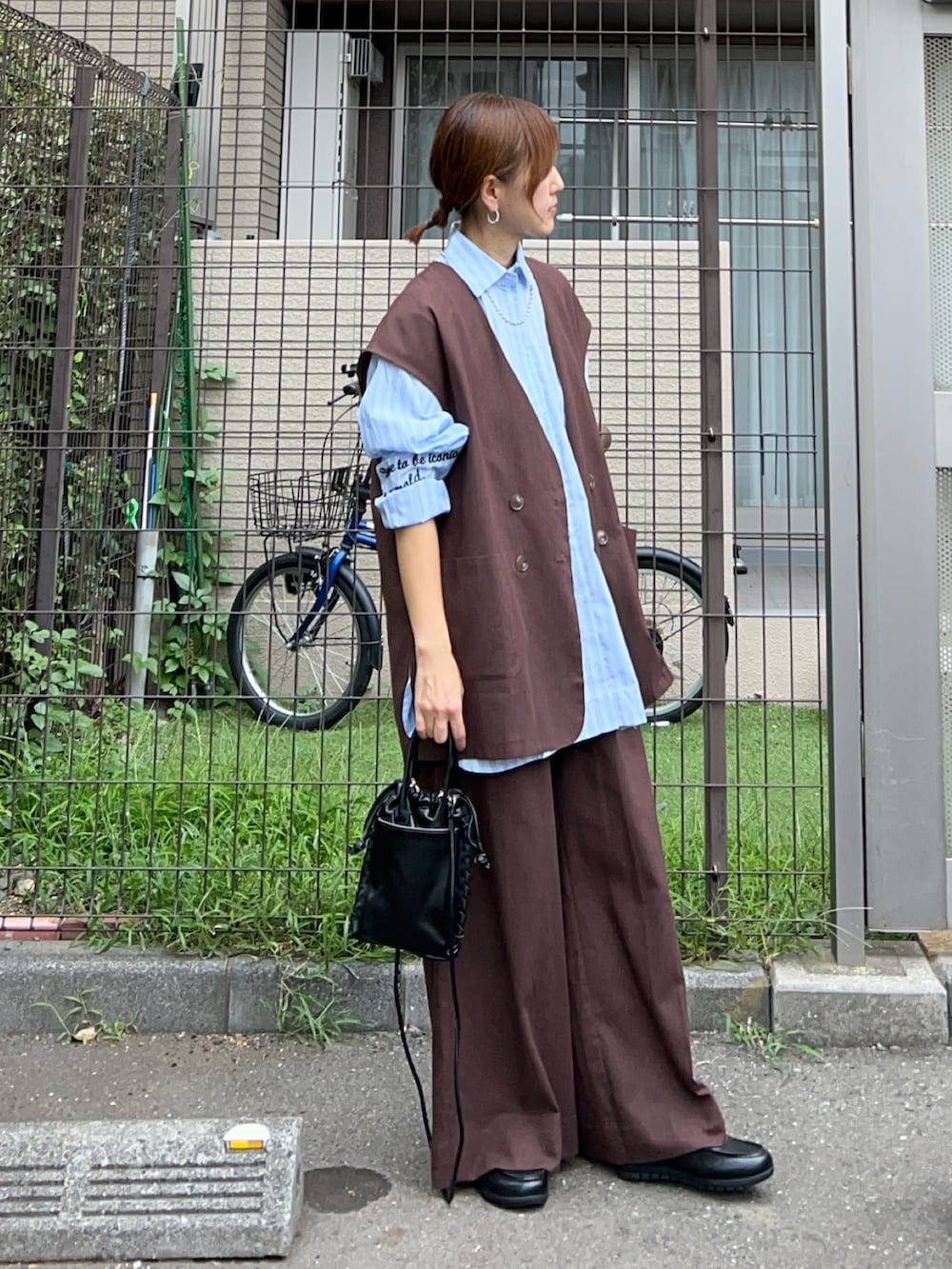 ブラウン系のベスト、ブラウン系のスラックス、ブルー系のシャツ/ブラウスを着用したレディースの秋コーディネートの3枚目の写真