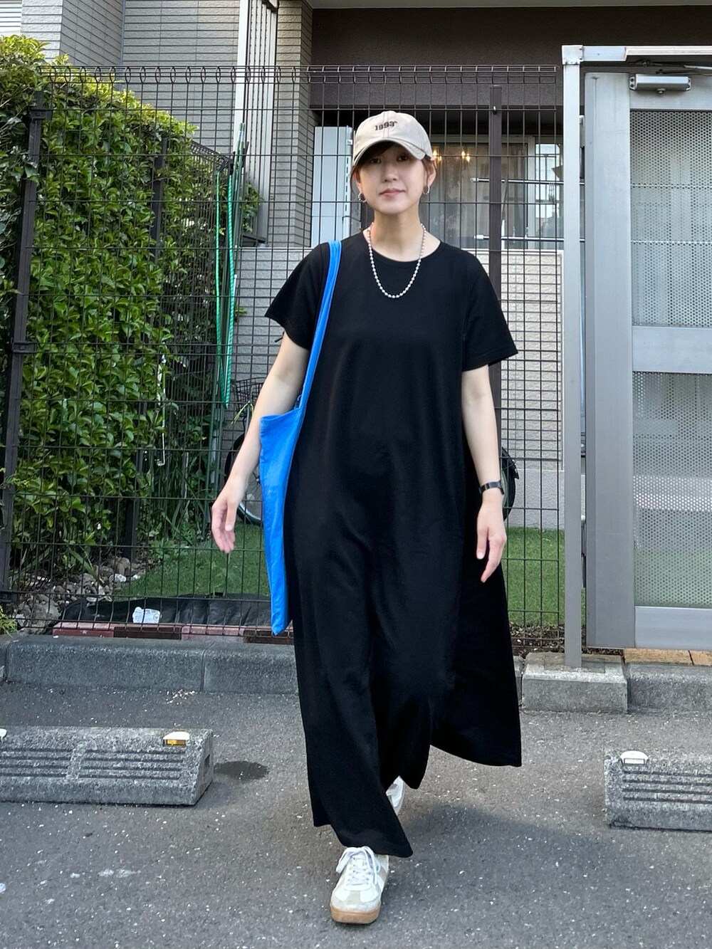 ブラック系のワンピース、ホワイト系のスニーカー、ベージュ系のキャップを着用したレディースの春コーディネートの5枚目の写真