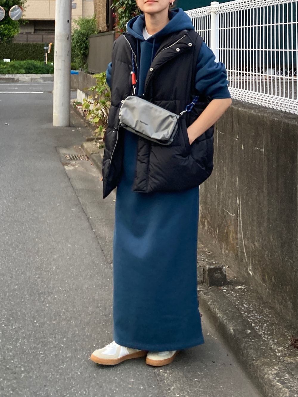 ブラック系のダウンベスト、ブルー系のワンピース、グレー系のショルダーバッグを着用したレディースの秋コーディネートの4枚目の写真