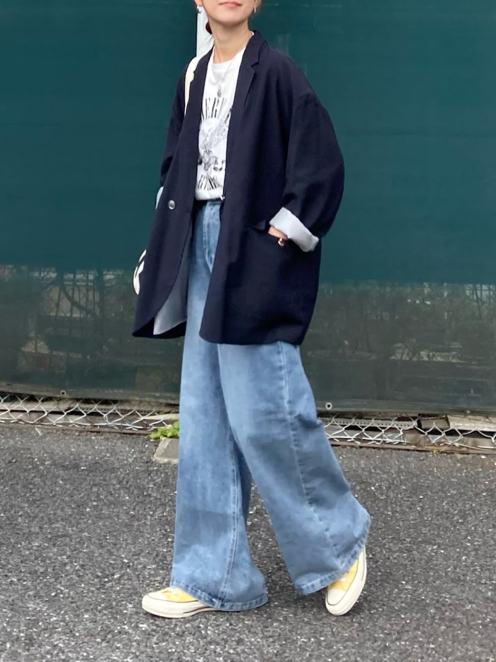 ホワイト系のTシャツ/カットソー、ブルー系のデニムパンツ、ブラック系のトートバッグを着用したレディースの春コーディネートの2枚目の写真