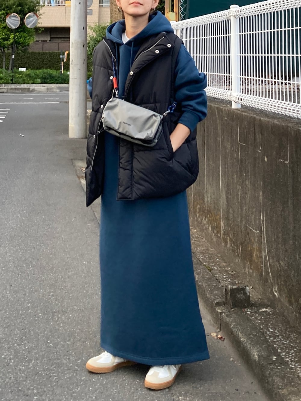 ブラック系のダウンベスト、ブルー系のワンピース、グレー系のショルダーバッグを着用したレディースの秋コーディネートの2枚目の写真
