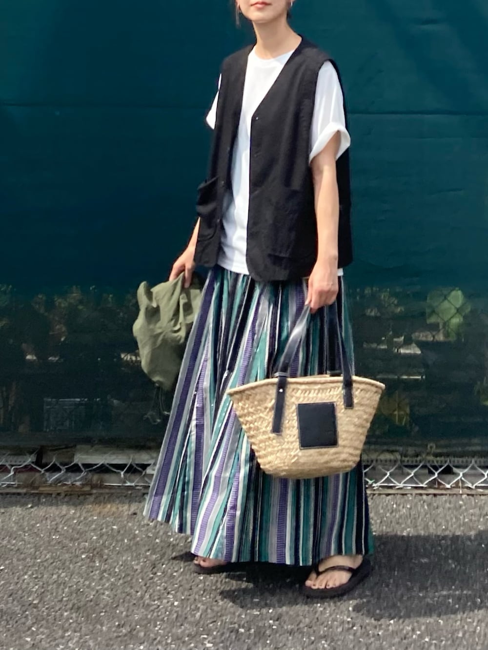 ホワイト系のTシャツ/カットソー、グリーン系のスカート、ブラック系のかごバッグを着用したレディースの夏コーディネートの2枚目の写真