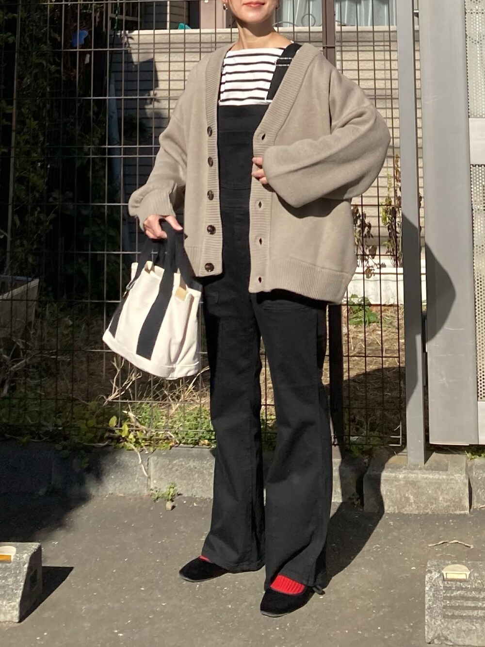 ベージュ系のカーディガン/ボレロ、ブラック系のサロペット/オーバーオール、ホワイト系のトートバッグを着用したレディースの冬コーディネートの3枚目の写真