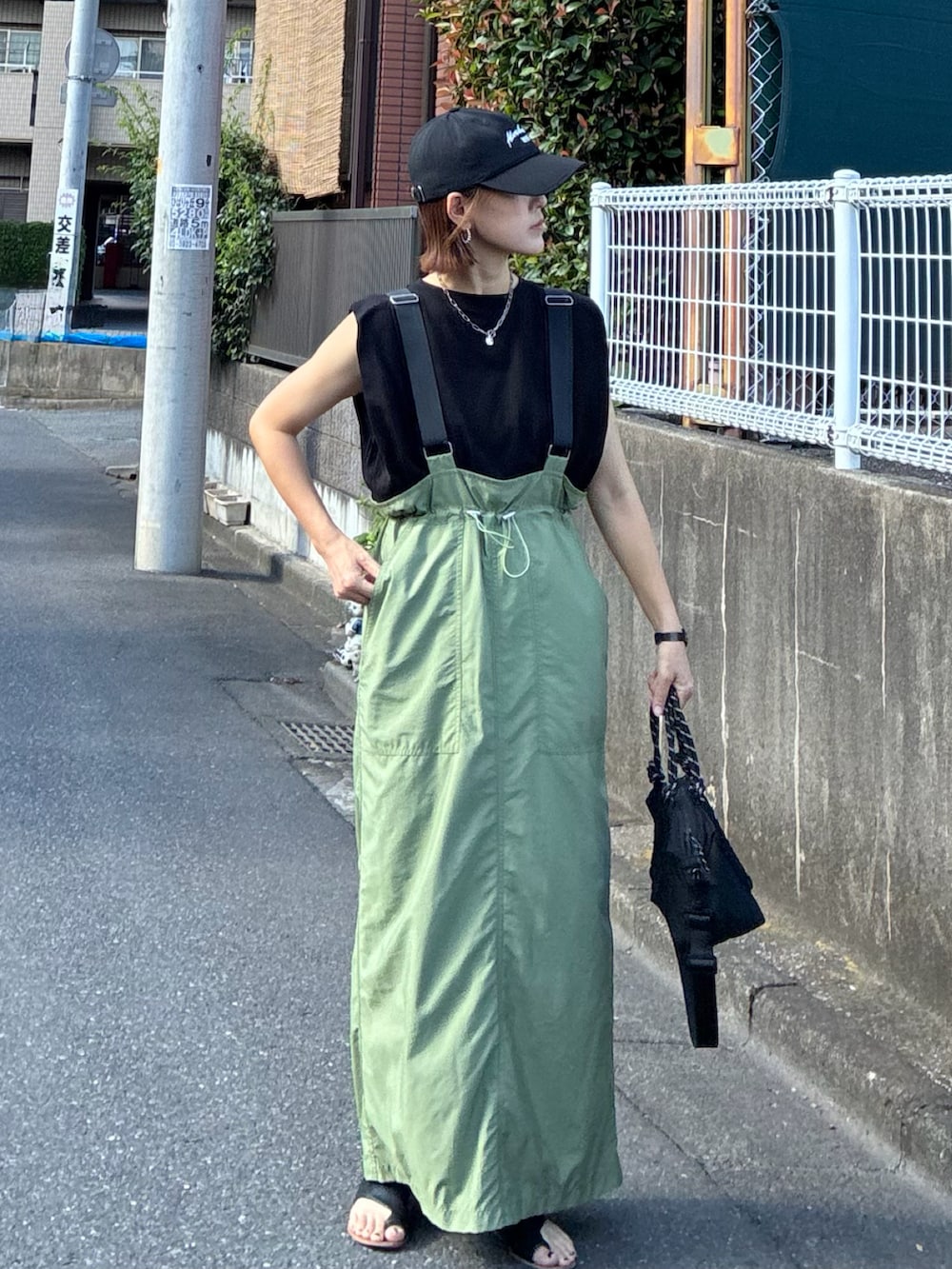ブラック系のTシャツ/カットソー、グリーン系のジャンパースカート、ブラック系のトートバッグを着用したレディースの夏コーディネートの4枚目の写真