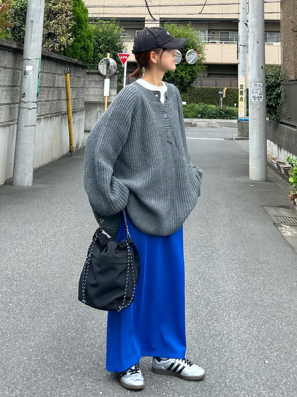 グレー系のニット/セーター、ブラック系のショルダーバッグ、ブルー系のスカートを着用したレディースの秋コーディネートの3枚目の写真