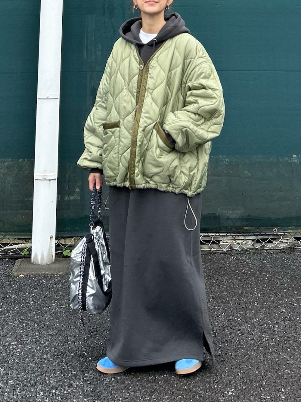 グレー系のワンピース、グリーン系のノーカラージャケット、シルバー系のトートバッグを着用したレディースの秋コーディネートの4枚目の写真