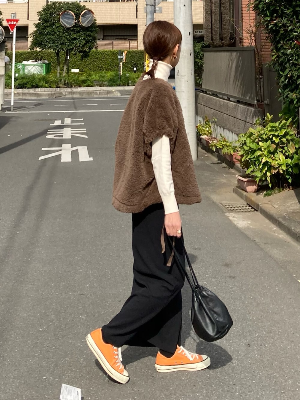 グリーン系のベスト、ブラック系のスカート、ブラック系のブーツを着用したレディースの秋コーディネートの3枚目の写真