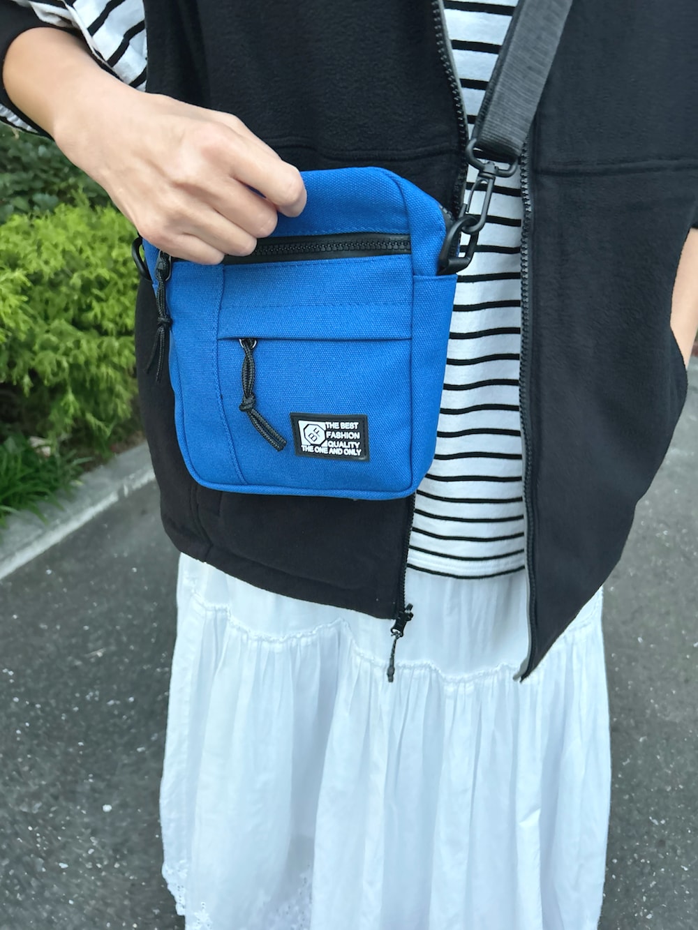 ブラック系のベスト、ブルー系のショルダーバッグ、ブラック系のTシャツ/カットソーを着用したレディースの秋コーディネートの5枚目の写真