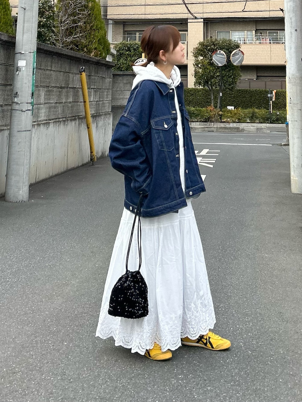 ブルー系のデニムジャケット、グレー系のパーカー、ホワイト系のスカートを着用したレディースの春コーディネートの2枚目の写真