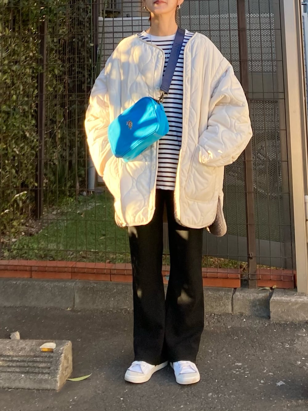 ホワイト系のブルゾン、ブルー系のショルダーバッグ、ブラック系のTシャツ/カットソーを着用したレディースの冬コーディネートの3枚目の写真