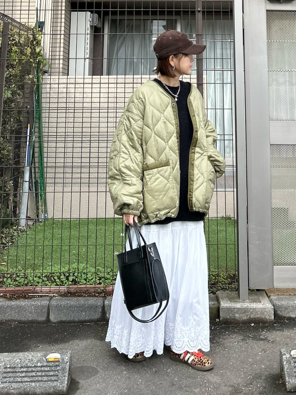 ブラック系のスウェット、ホワイト系のスカート、グリーン系のブルゾンを着用したレディースの冬コーディネートの4枚目の写真