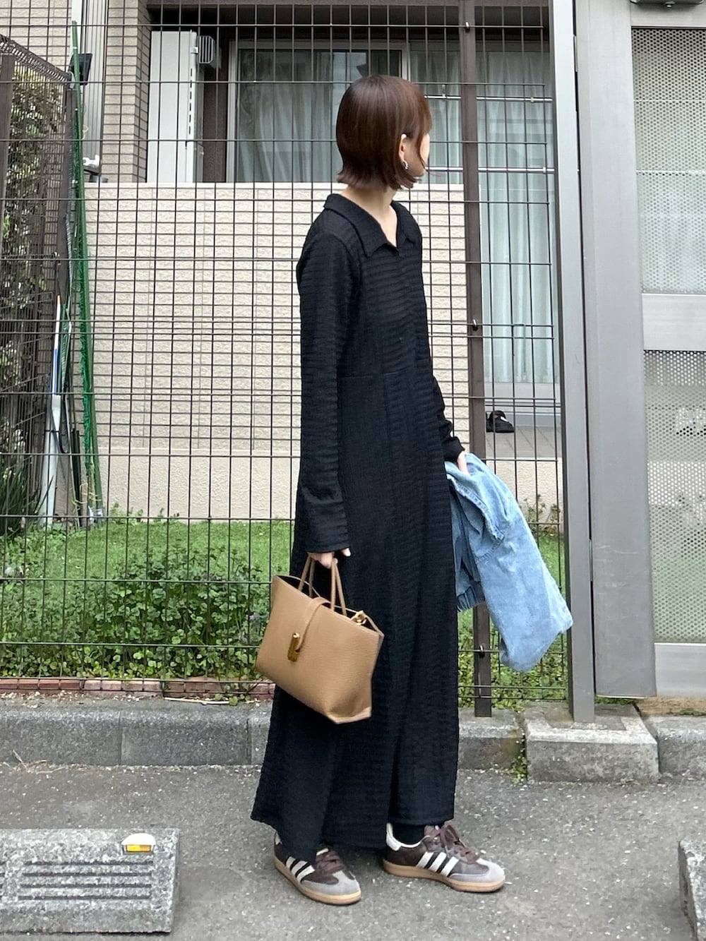 ブルー系のデニムジャケット、ブラック系のワンピース、ブラウン系のハンドバッグを着用したレディースの冬コーディネートの4枚目の写真