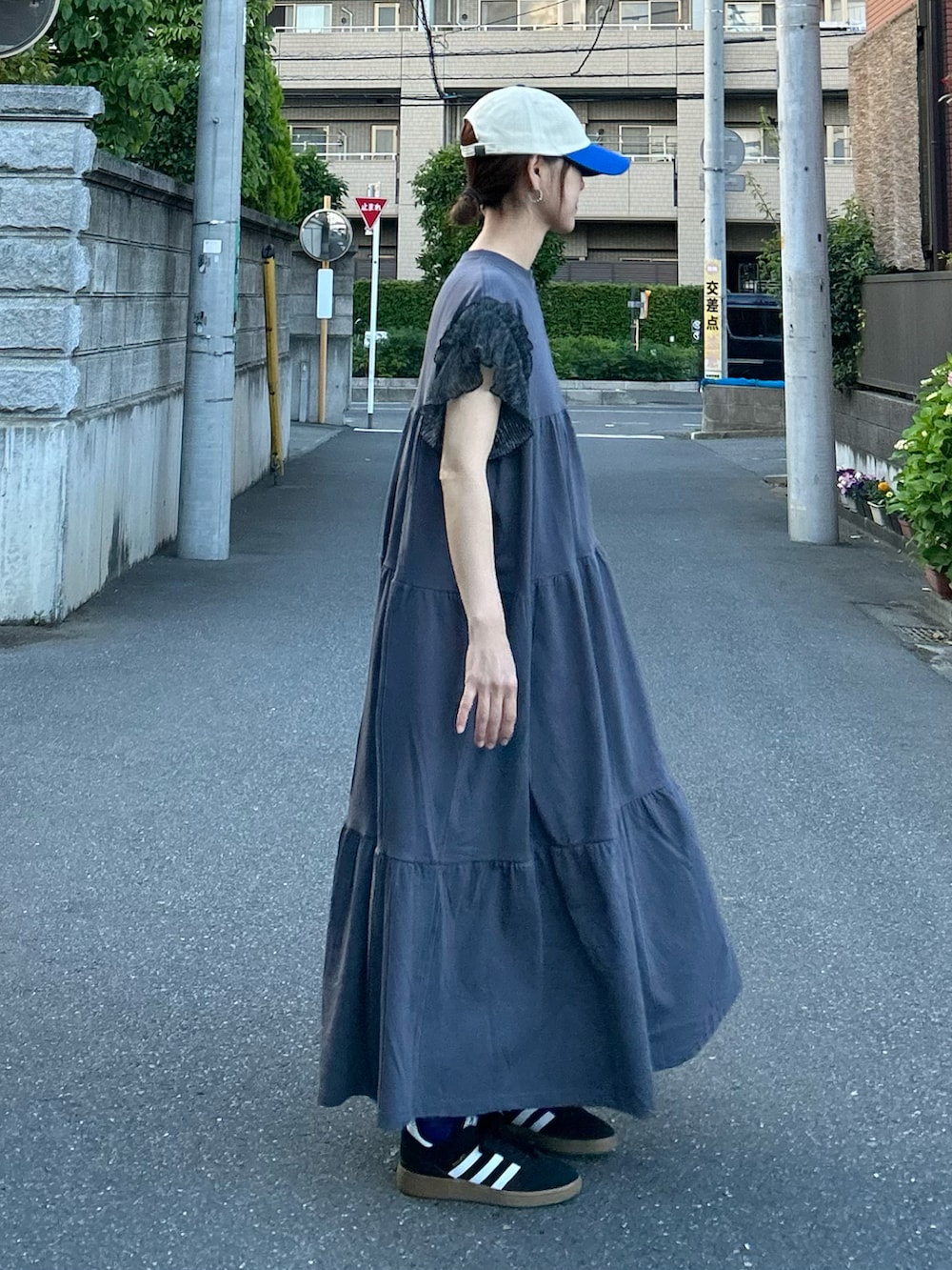 ブラック系のワンピース、ブラック系のトートバッグ、ブルー系のキャップを着用したレディースの夏コーディネートの2枚目の写真