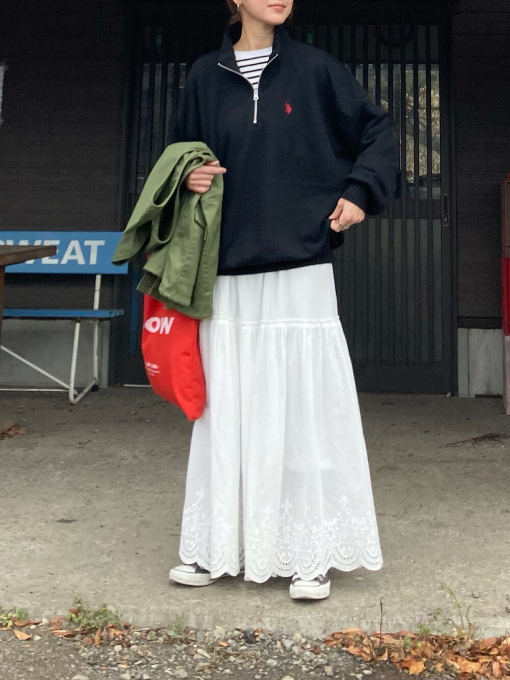 ブラック系のスウェット、ホワイト系のスカート、レッド系のトートバッグを着用したレディースの冬コーディネートの3枚目の写真