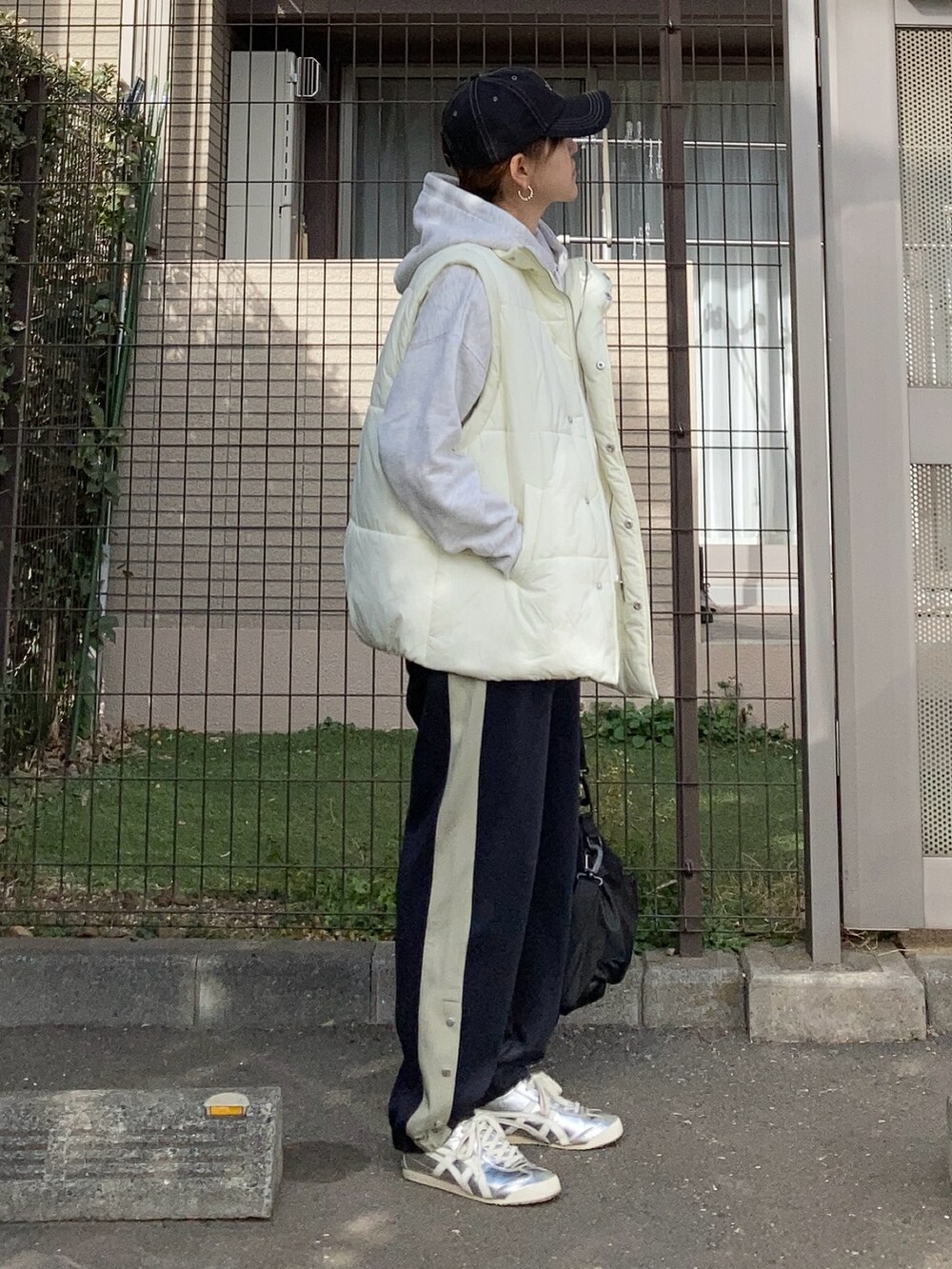 ホワイト系のダウンベスト、グレー系のパーカー、ブルー系のスウェットパンツを着用したレディースの冬コーディネートの3枚目の写真