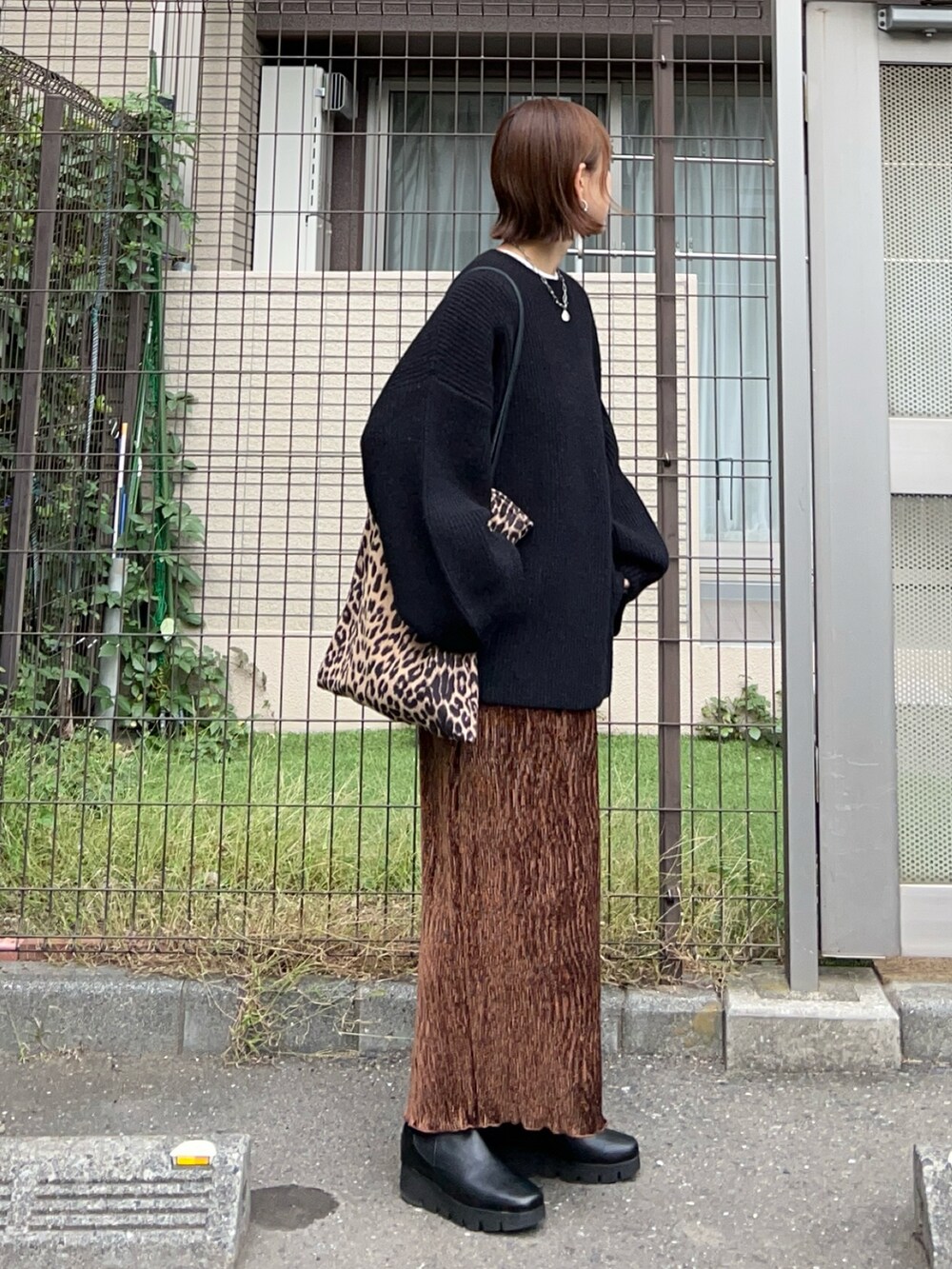 ブラウン系のスカート、ブラウン系のトートバッグ、ブラック系のニット/セーターを着用したレディースの秋コーディネートの2枚目の写真