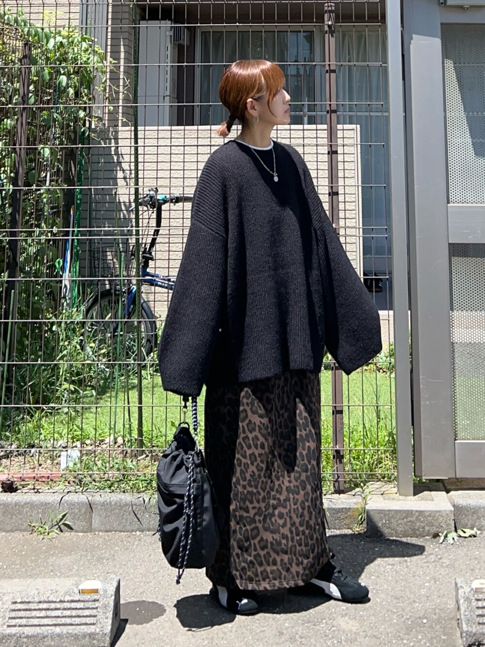 ブラック系のニット/セーター、ブラック系のトートバッグ、ブラウン系のスカートを着用したレディースの夏コーディネートの2枚目の写真