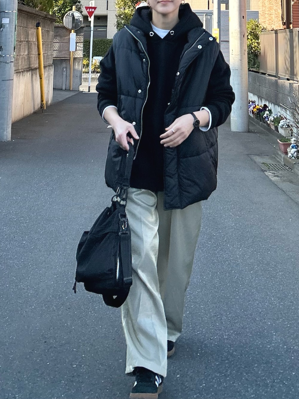 ブラック系のダウンベスト、ブラック系のパーカー、ベージュ系のその他パンツを着用したレディースの春コーディネートの3枚目の写真