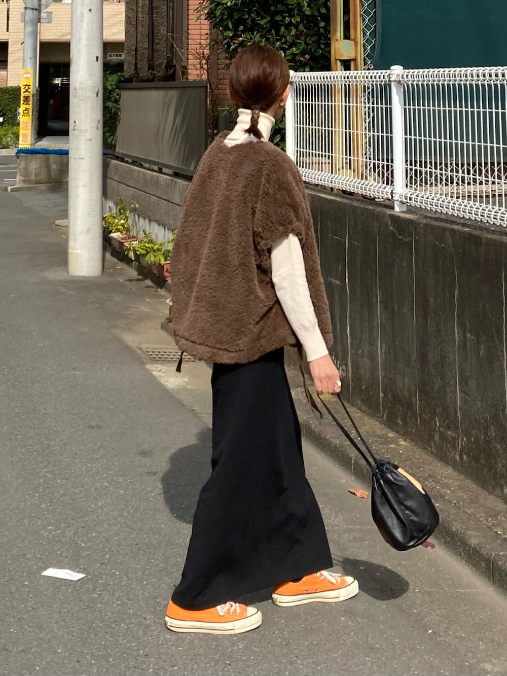 グリーン系のベスト、ブラック系のスカート、ブラック系のブーツを着用したレディースの秋コーディネートの4枚目の写真