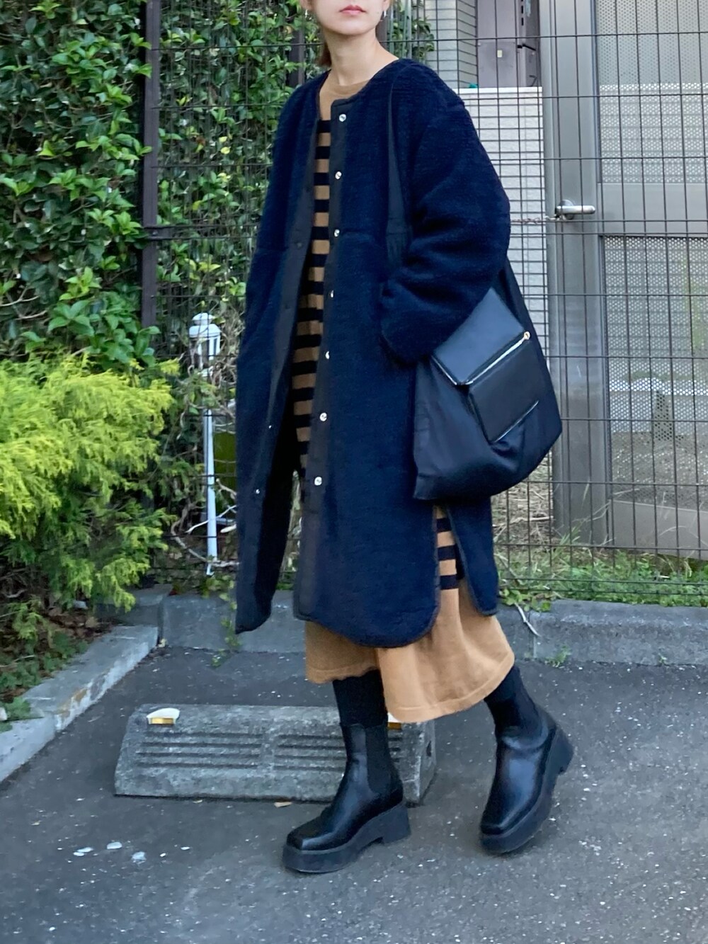 ブルー系のノーカラージャケット、ブラック系のハンドバッグ、ブラウン系のワンピースを着用したレディースの冬コーディネートの2枚目の写真