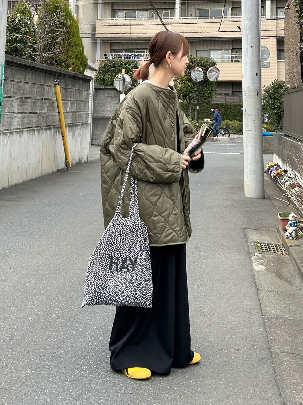 グリーン系のノーカラージャケット、ホワイト系のニット/セーター、ブラック系のサロペット/オーバーオールを着用したレディースの春コーディネートの4枚目の写真