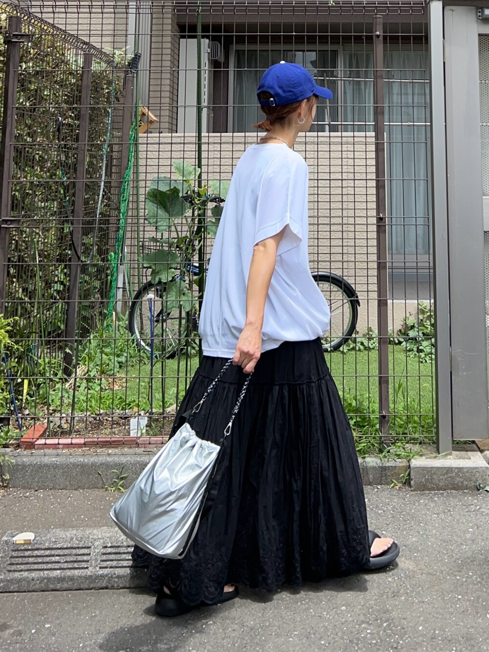 ホワイト系のTシャツ/カットソー、シルバー系のトートバッグ、ブラック系のスカートを着用したレディースの夏コーディネートの2枚目の写真