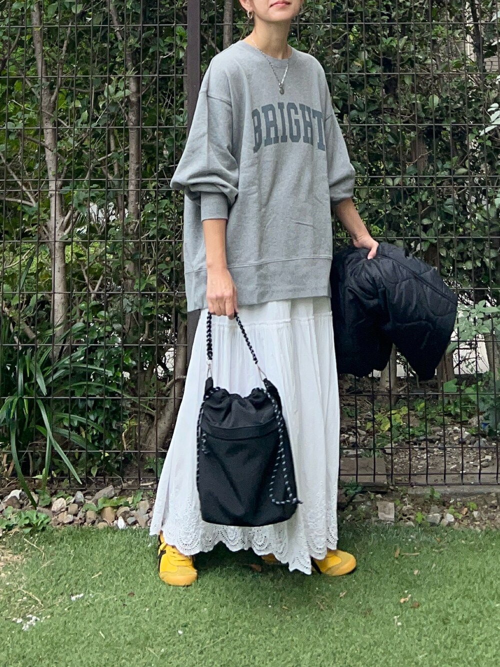 グレー系のスウェット、ホワイト系のスカート、ブラック系のトートバッグを着用したレディースの秋コーディネートの4枚目の写真