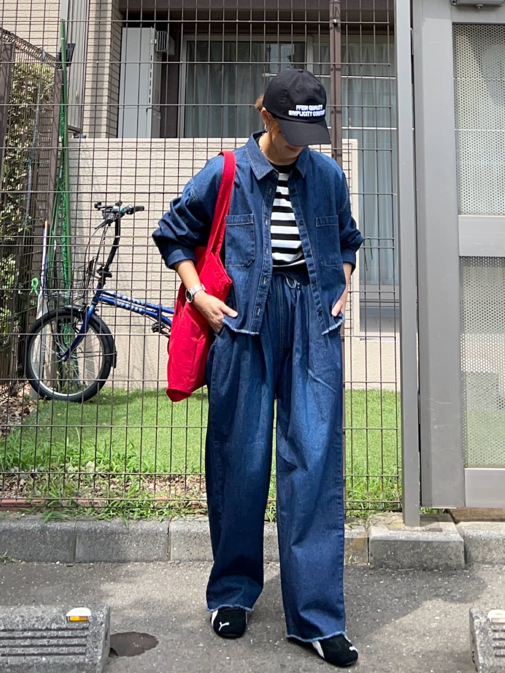 レッド系のトートバッグ、ブルー系のシャツ/ブラウス、ブルー系のデニムパンツを着用したレディースの夏コーディネートの2枚目の写真