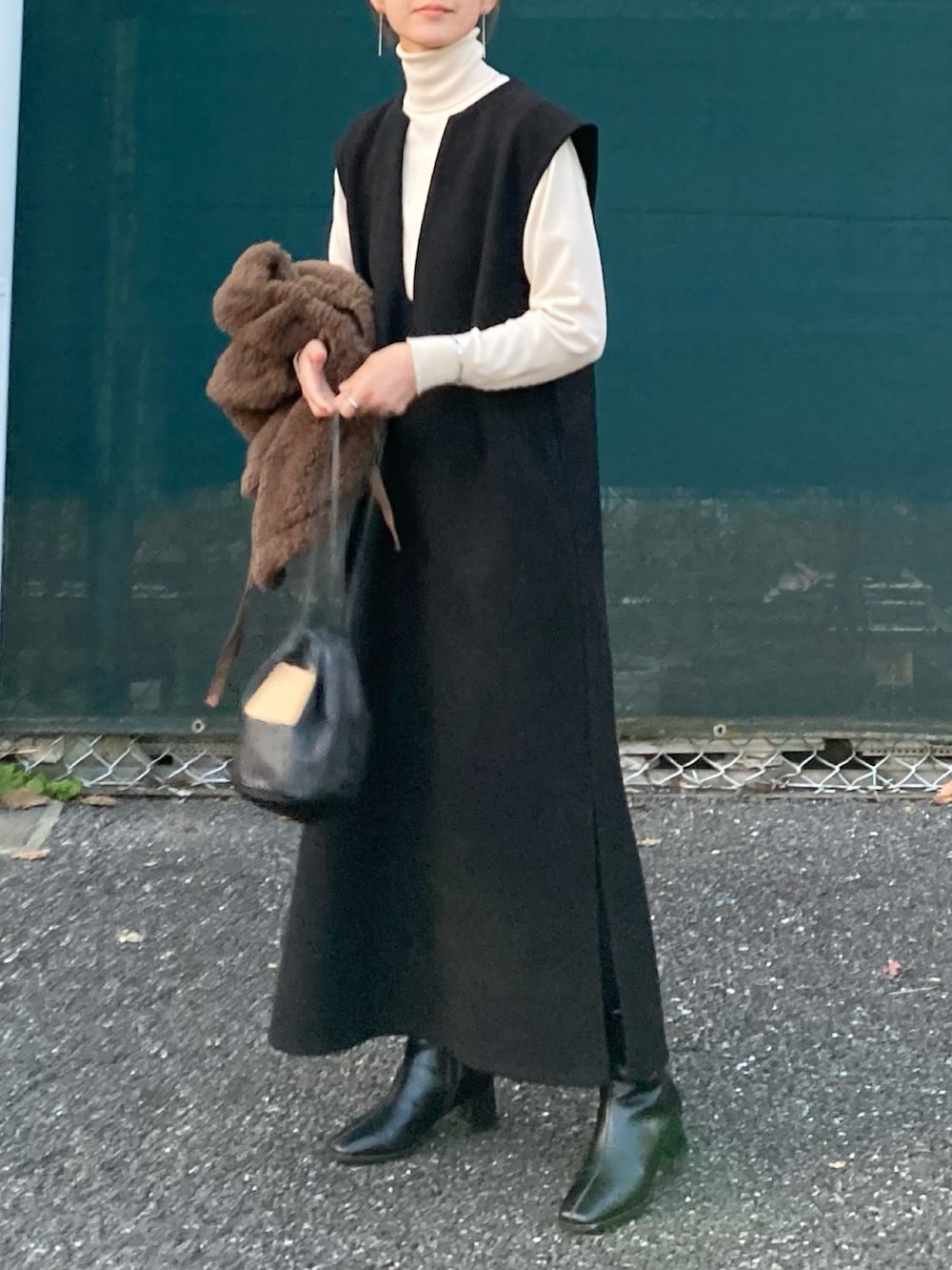 ブラック系のワンピース、ブラック系のハンドバッグ、ブラック系のブーツを着用したレディースの冬コーディネートの3枚目の写真