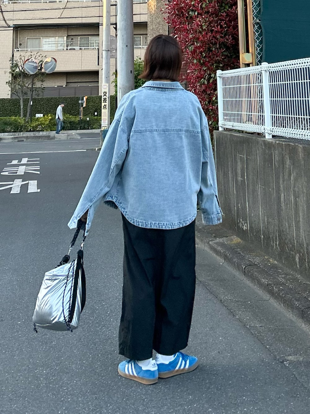 ブルー系のデニムジャケット、ブラック系のジャンパースカート、シルバー系のショルダーバッグを着用したレディースの春コーディネートの4枚目の写真