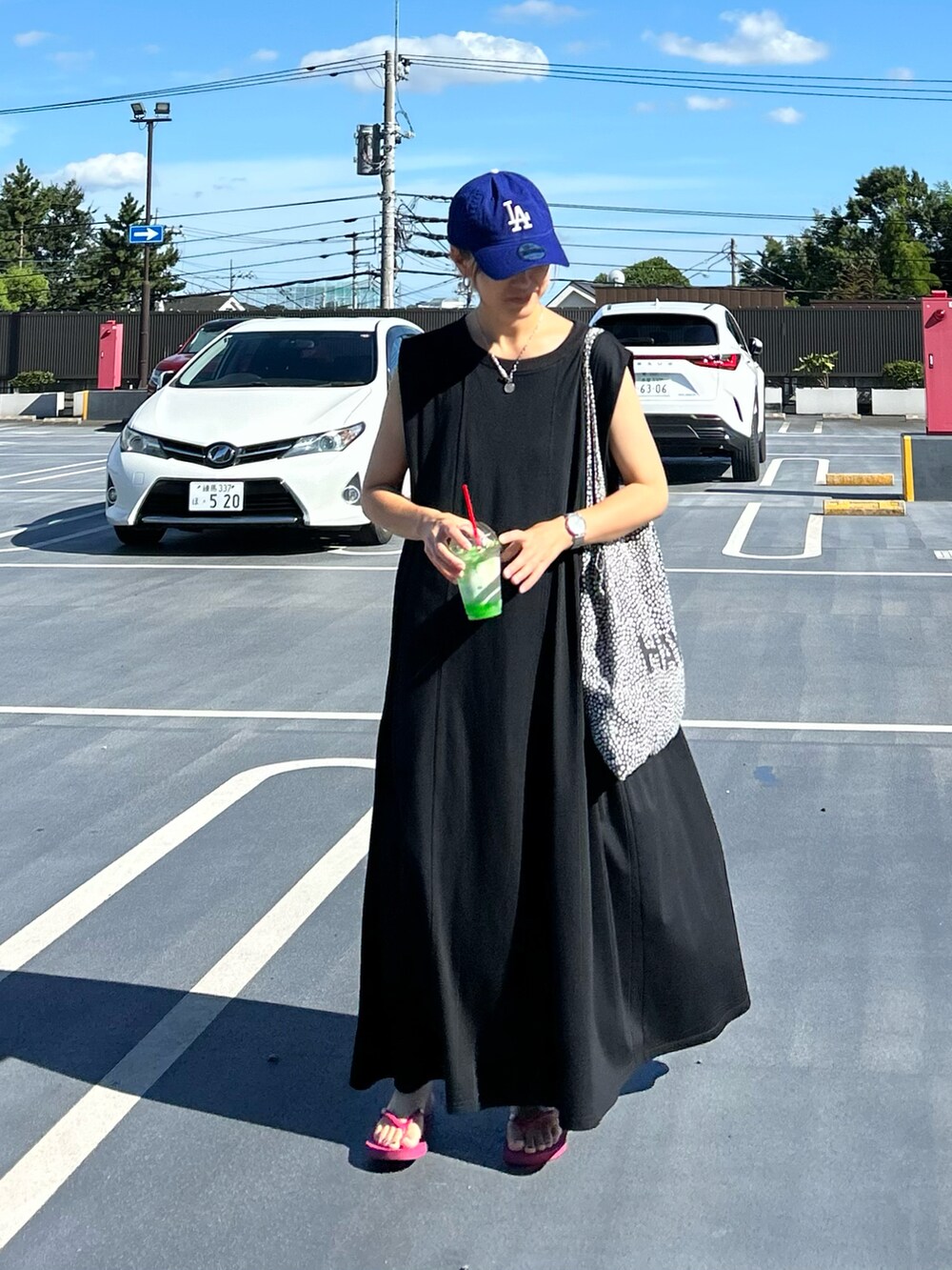 ブラック系のワンピース、パープル系のサンダル、ブルー系のキャップを着用したレディースの夏コーディネートの5枚目の写真