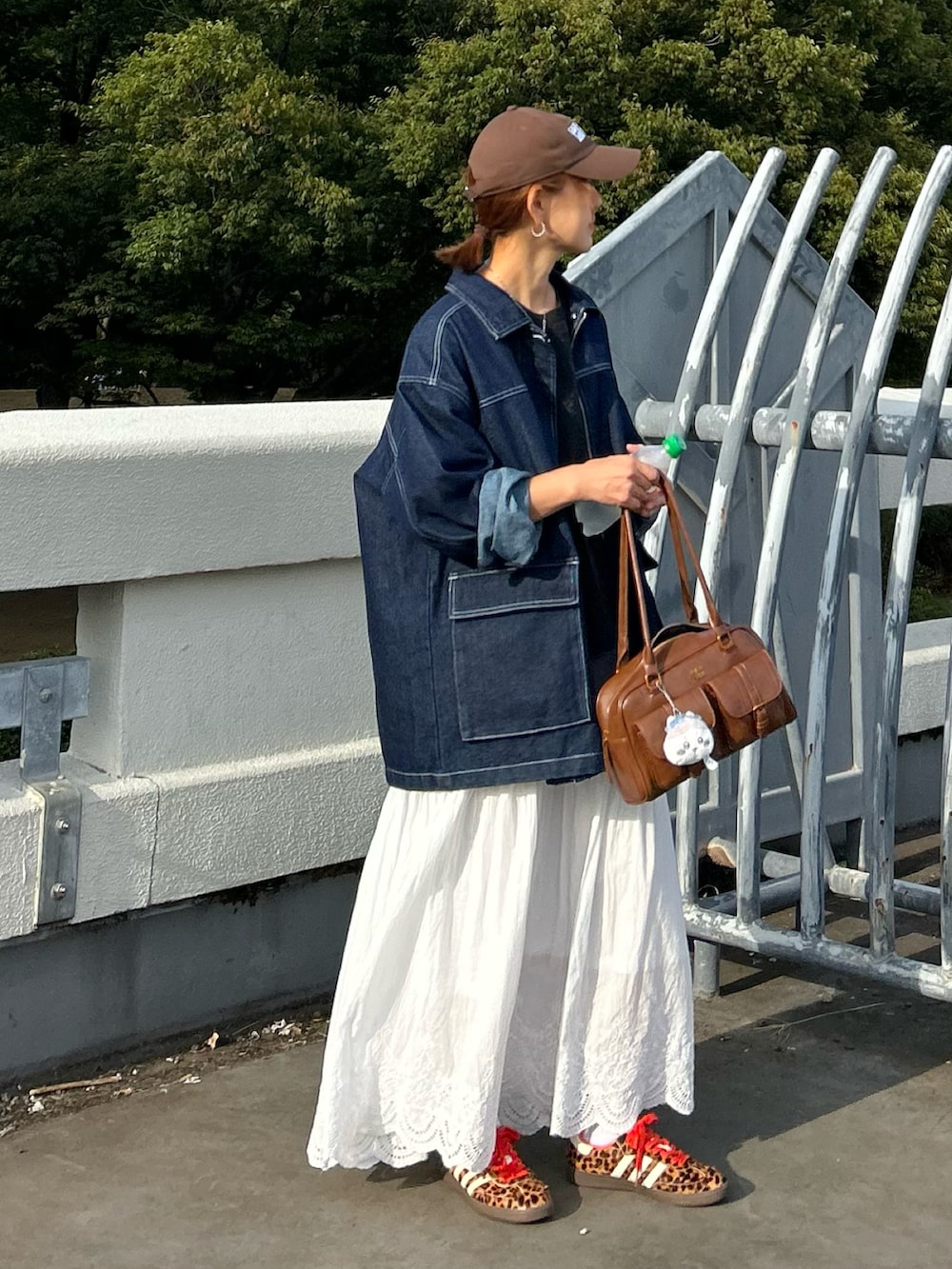 ホワイト系のスカート、ブラウン系のハンドバッグ、ブルー系のデニムジャケットを着用したレディースの秋コーディネートの2枚目の写真