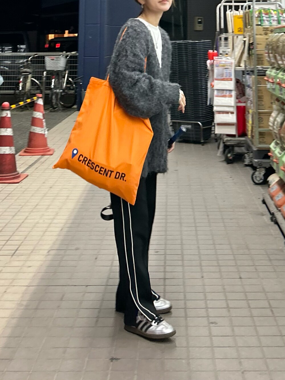 ブラック系のスウェットパンツ、オレンジ系のトートバッグ、グレー系のカーディガン/ボレロを着用したレディースの秋コーディネートの4枚目の写真