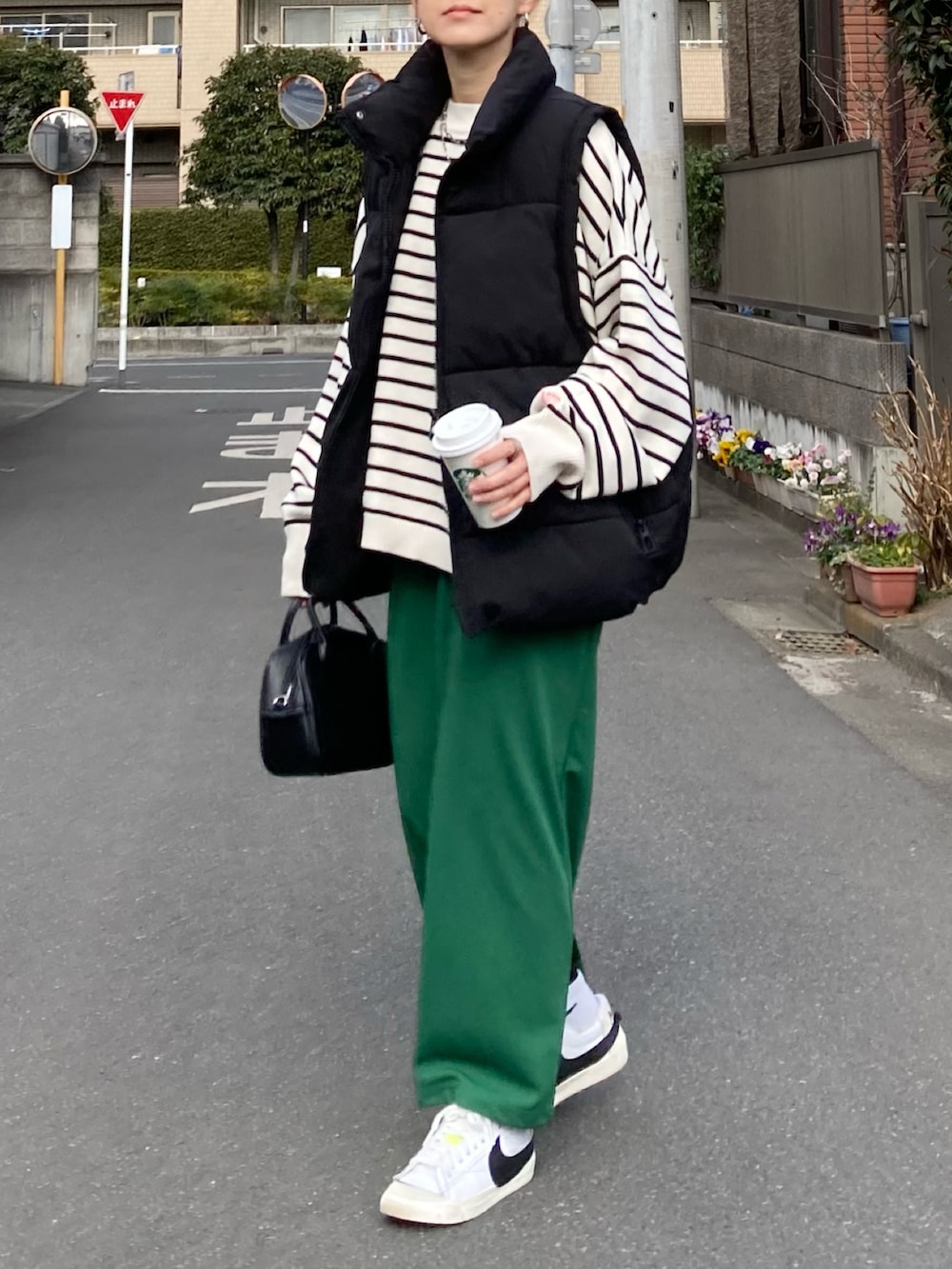 ブラック系のダウンベスト、ホワイト系のニット/セーター、グリーン系のスカートを着用したレディースの冬コーディネートの4枚目の写真