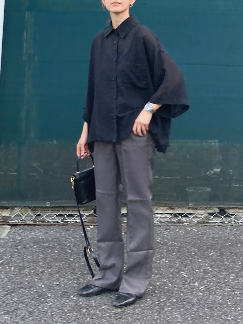 ブラック系のシャツ/ブラウス、グレー系のスラックス、ブラック系のショルダーバッグを着用したレディースの夏コーディネートの2枚目の写真