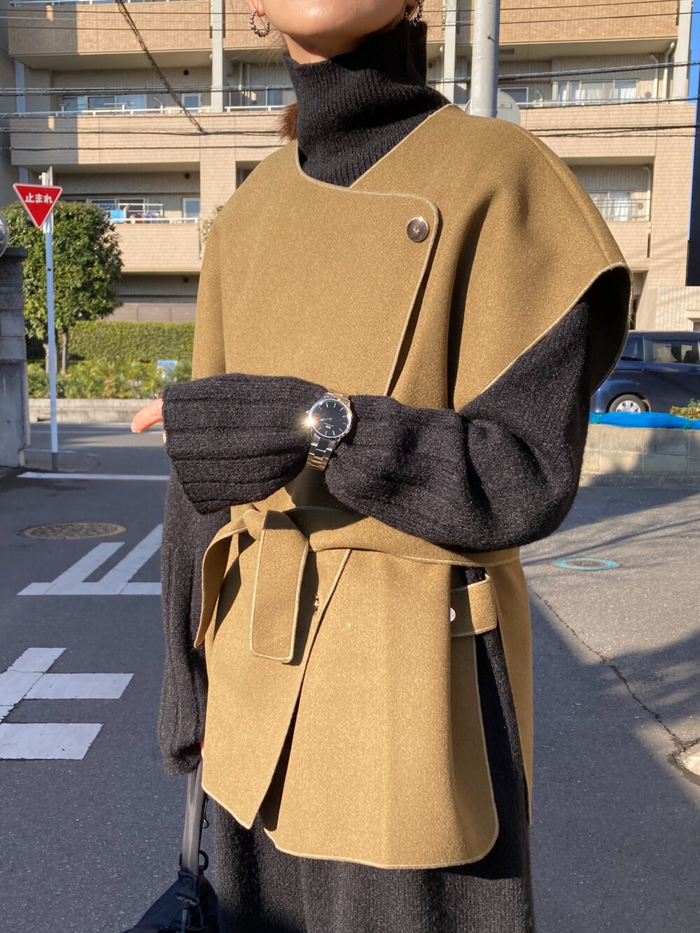 グリーン系のベスト、ブラック系のワンピース、ブラック系のショルダーバッグを着用したレディースの冬コーディネートの4枚目の写真