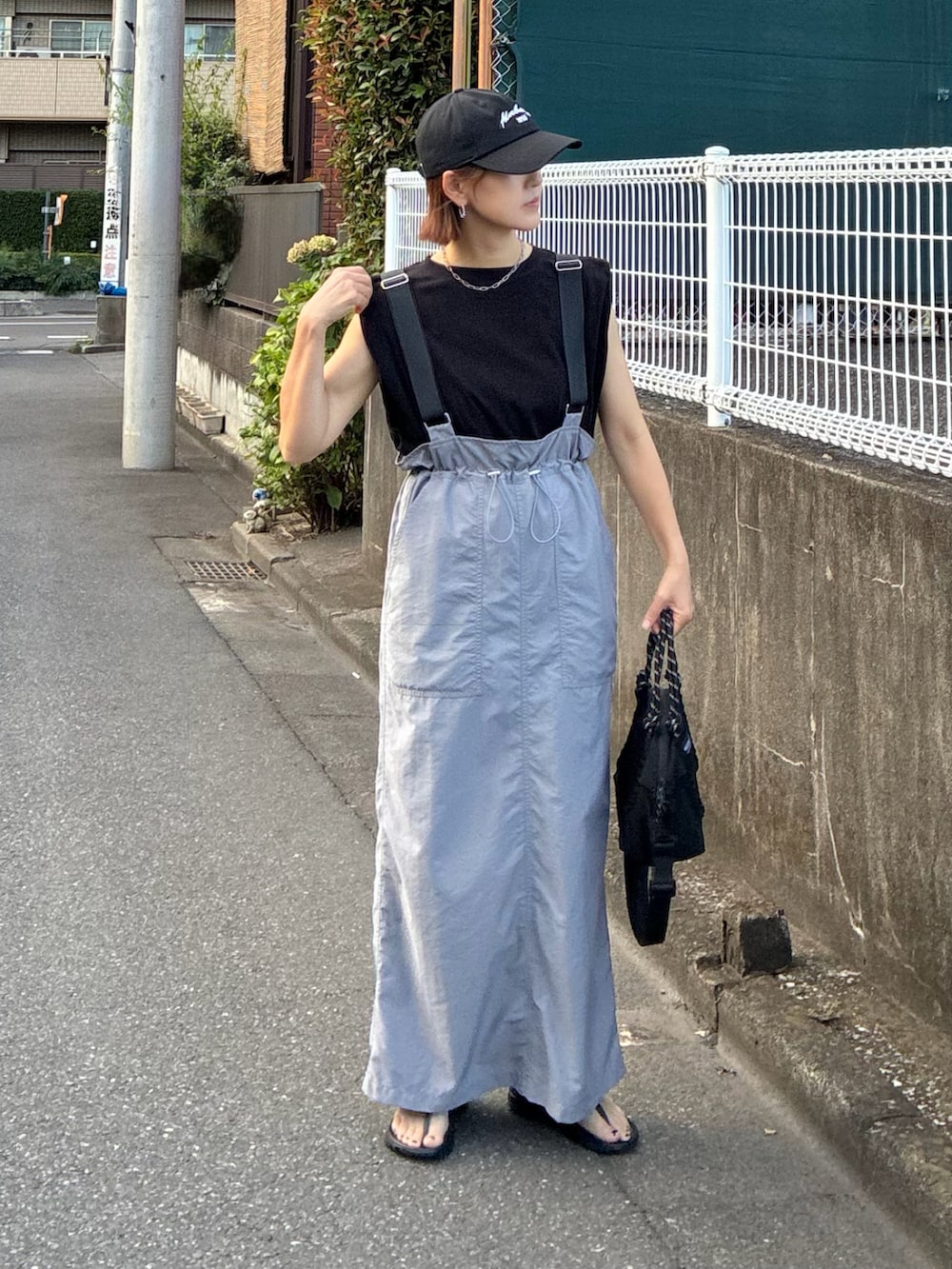 グレー系のジャンパースカート、ブラック系のサンダル、ブラック系のTシャツ/カットソーを着用したレディースの秋コーディネートの4枚目の写真
