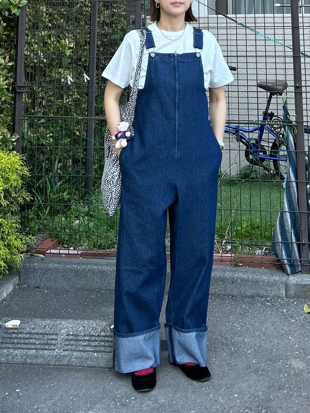 ブルー系のサロペット/オーバーオール、ブラック系のTシャツ/カットソー、ベージュ系のチャームを着用したレディースの春コーディネートの2枚目の写真