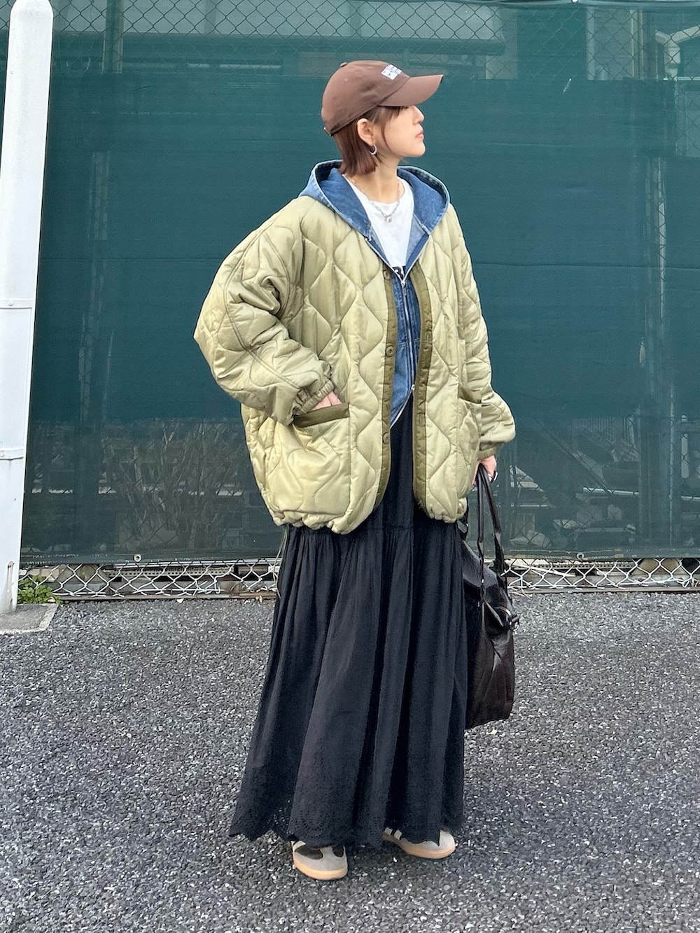 ブラック系のスカート、グリーン系のブルゾン、ブラウン系のトートバッグを着用したレディースの春コーディネートの3枚目の写真