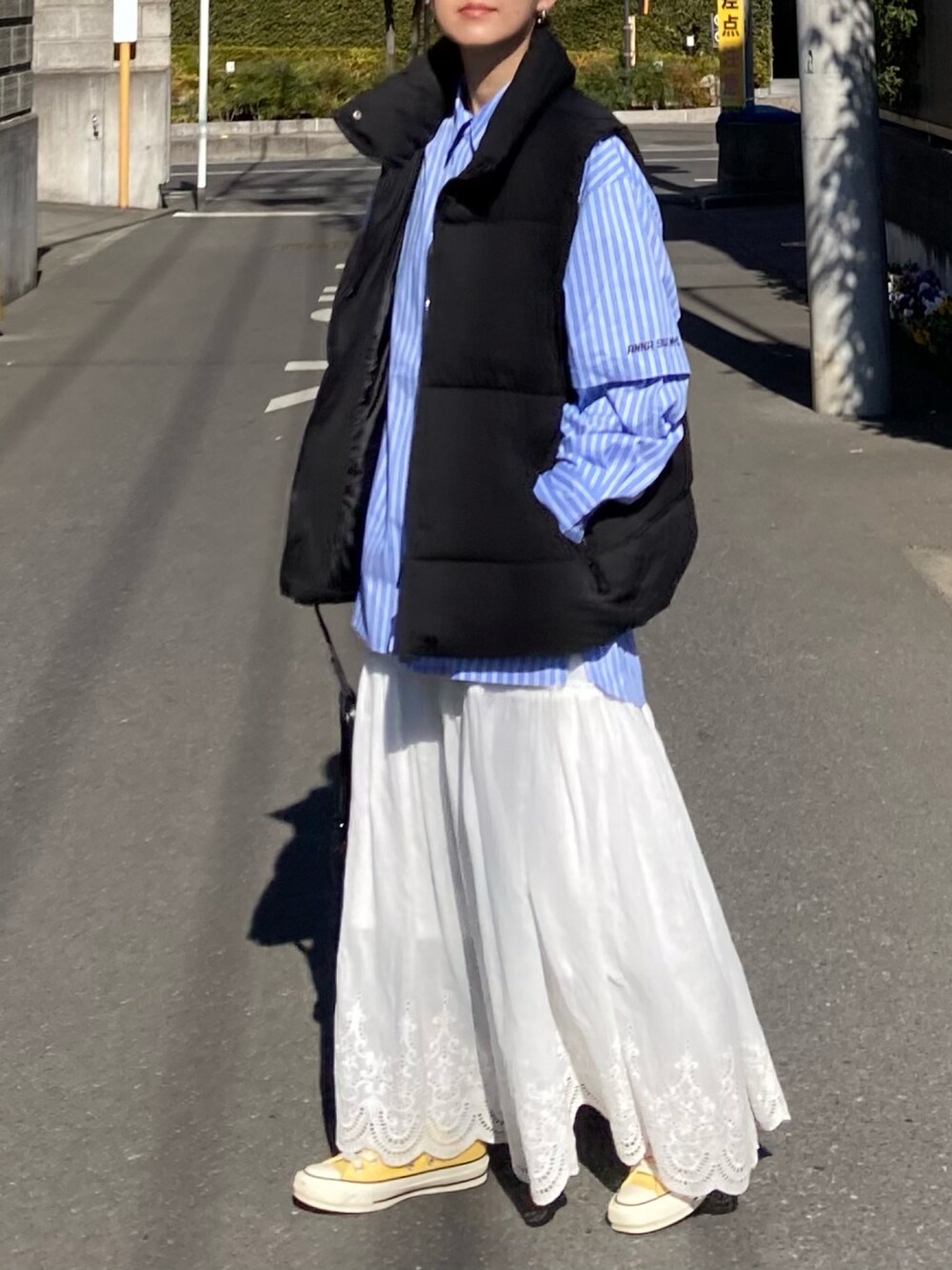 ブラック系のダウンベスト、ブルー系のシャツ/ブラウス、ブラック系のトートバッグを着用したレディースの冬コーディネートの3枚目の写真