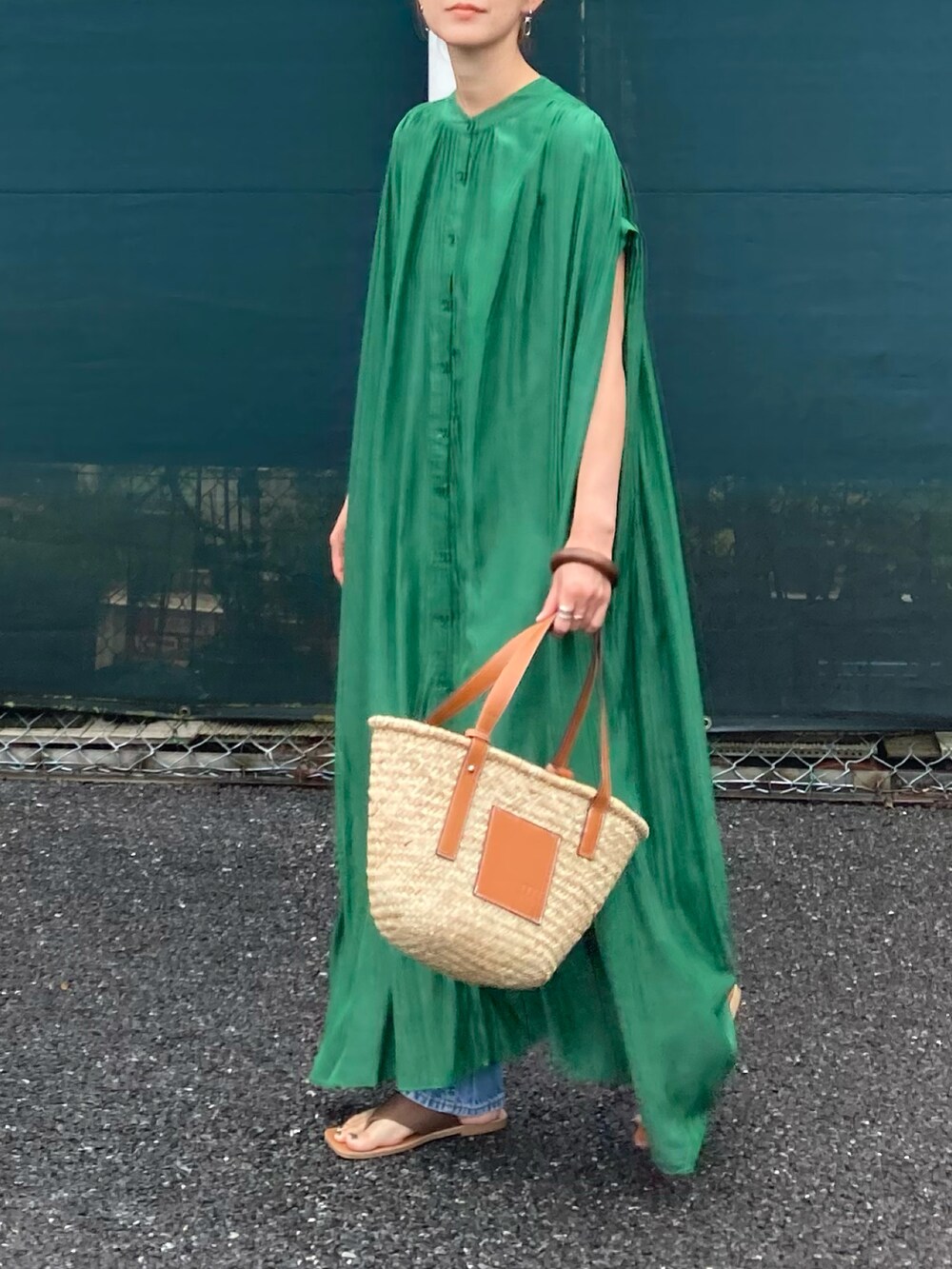 グリーン系のシャツワンピース、ブラウン系のかごバッグ、ブルー系のデニムパンツを着用したレディースの夏コーディネートの4枚目の写真