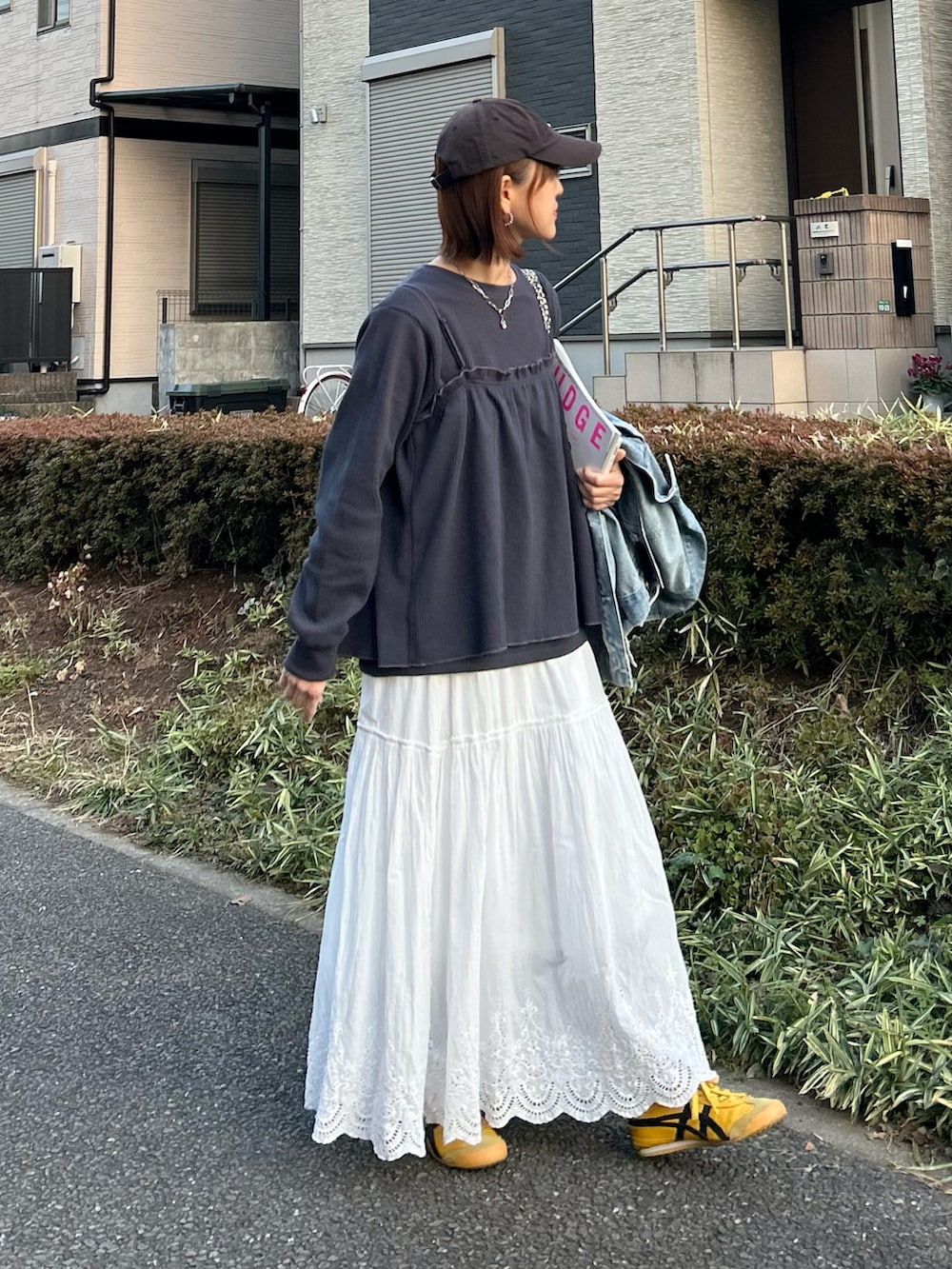 ホワイト系のスカート、グレー系のアンサンブル、イエロー系のスニーカーを着用したレディースの冬コーディネートの4枚目の写真