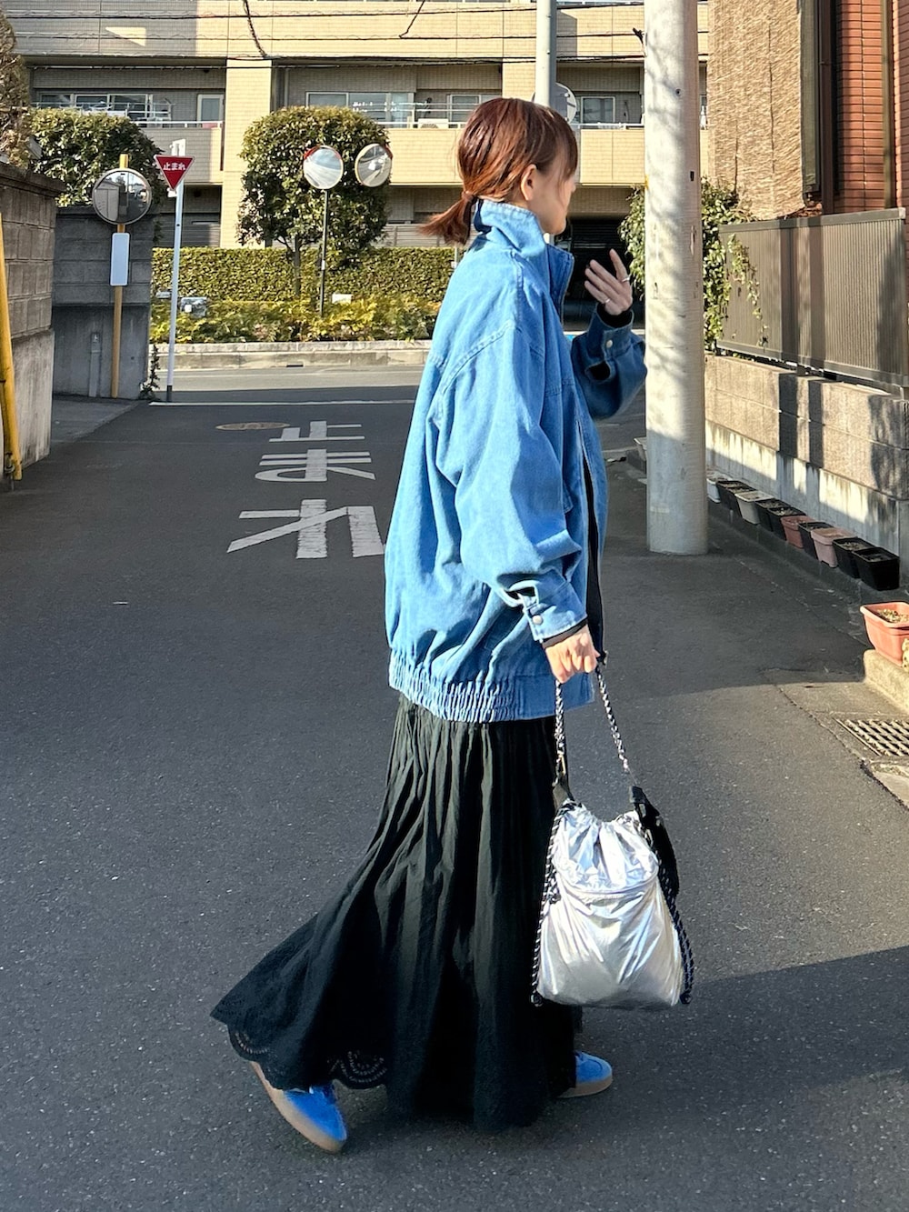 ブルー系のデニムジャケット、ブラック系のスカート、シルバー系のショルダーバッグを着用したレディースの春コーディネートの2枚目の写真