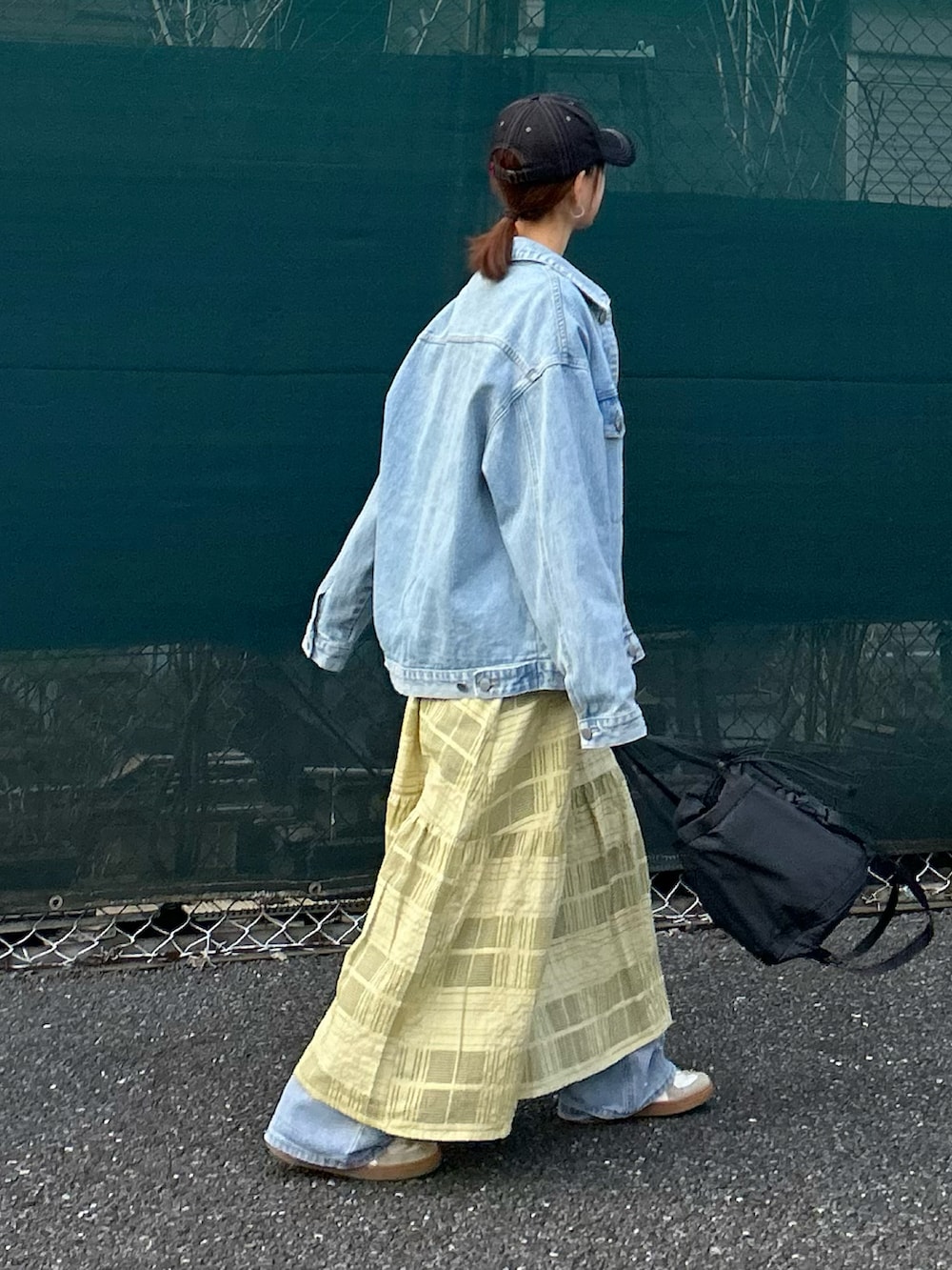 ブルー系のデニムジャケット、グリーン系のワンピース、ブルー系のデニムパンツを着用したレディースの春コーディネートの3枚目の写真