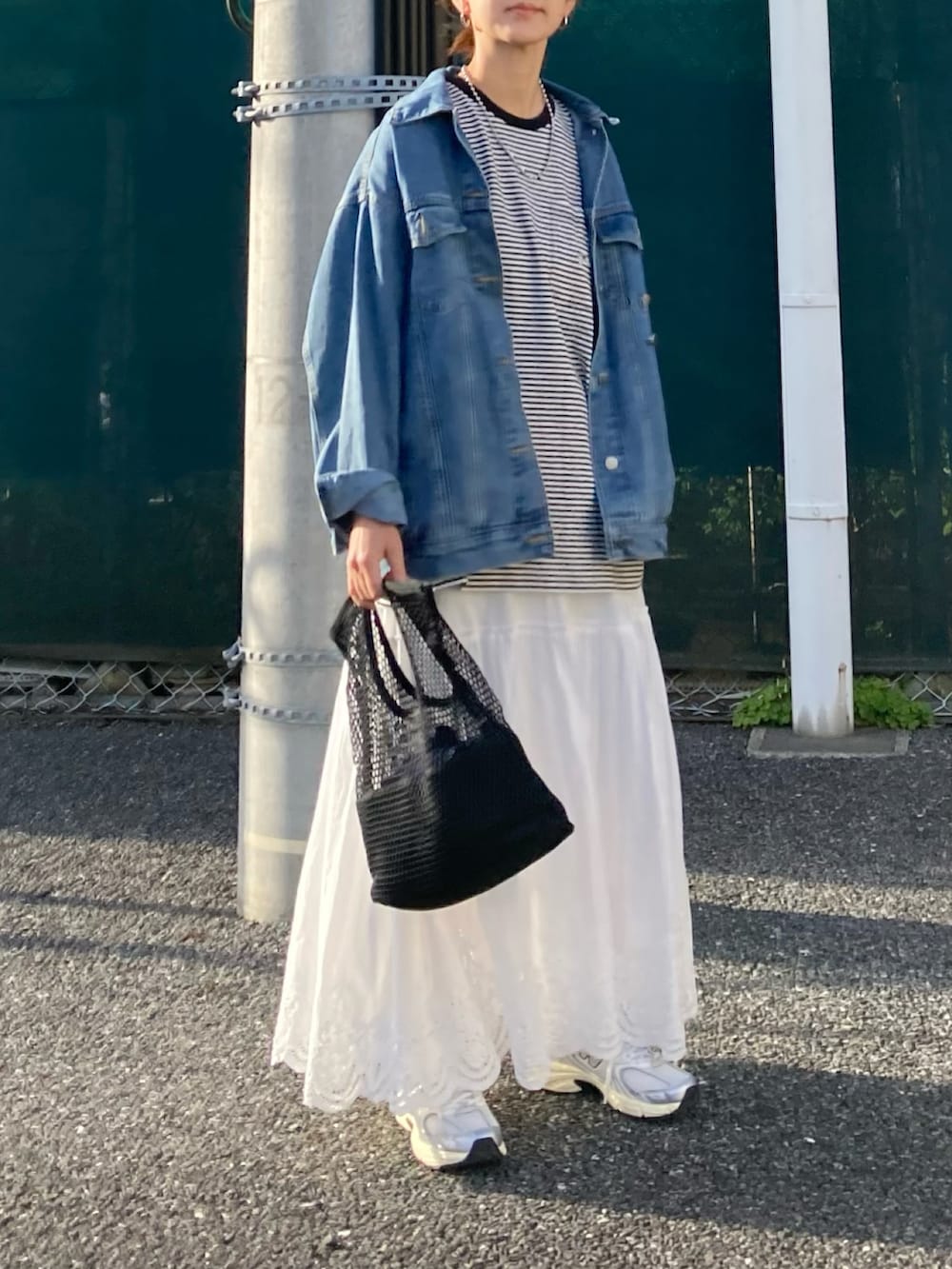 ブラック系のTシャツ/カットソー、ブルー系のデニムジャケット、ホワイト系のスカートを着用したレディースの春コーディネートの2枚目の写真