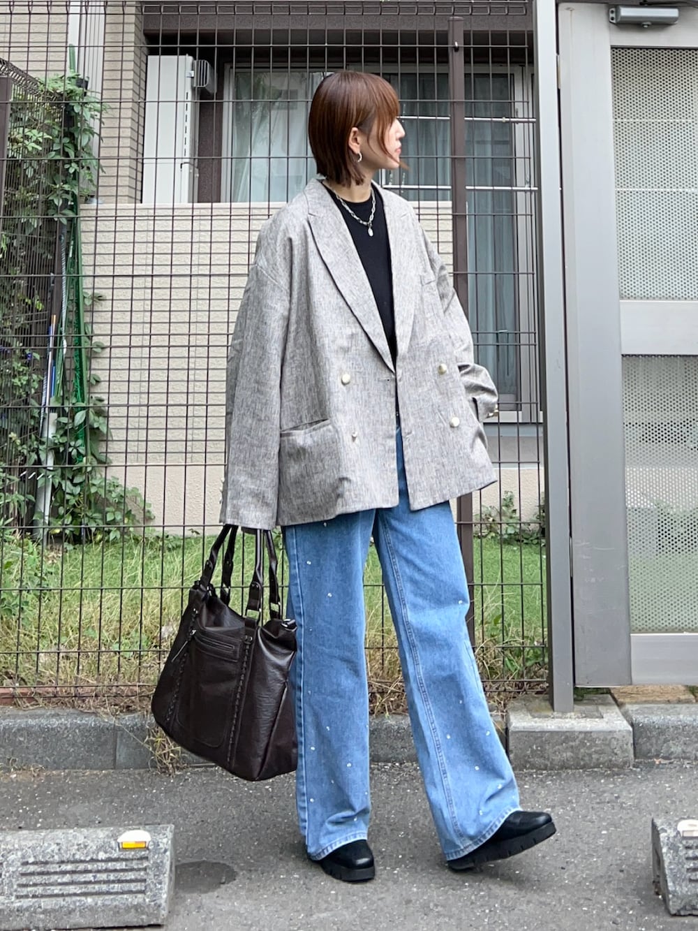 ベージュ系のテーラードジャケット、ブラウン系のトートバッグ、ブラック系のニット/セーターを着用したレディースの秋コーディネートの4枚目の写真