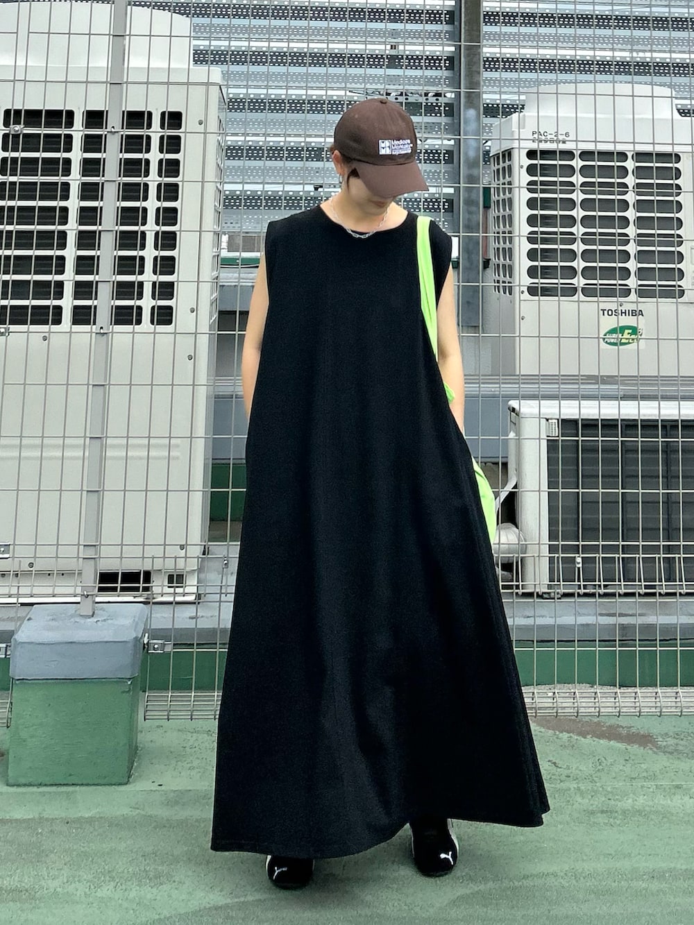 ブラック系のワンピース、グリーン系のトートバッグ、ブラック系のスニーカーを着用したレディースの夏コーディネートの3枚目の写真