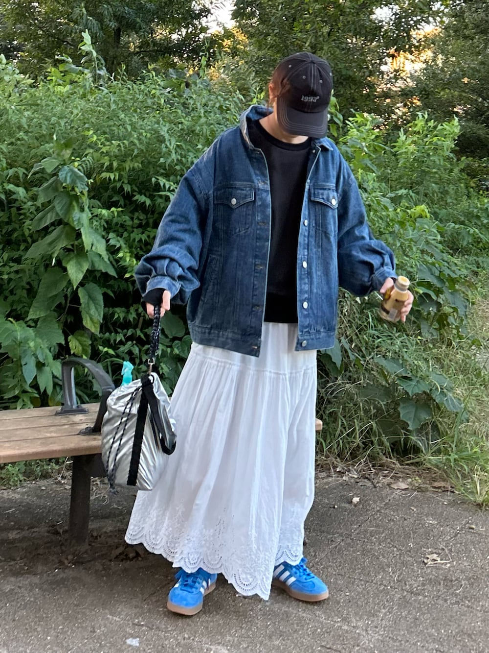 ホワイト系のスカート、ブルー系のデニムジャケット、ブラック系のスウェットを着用したレディースの秋コーディネートの4枚目の写真