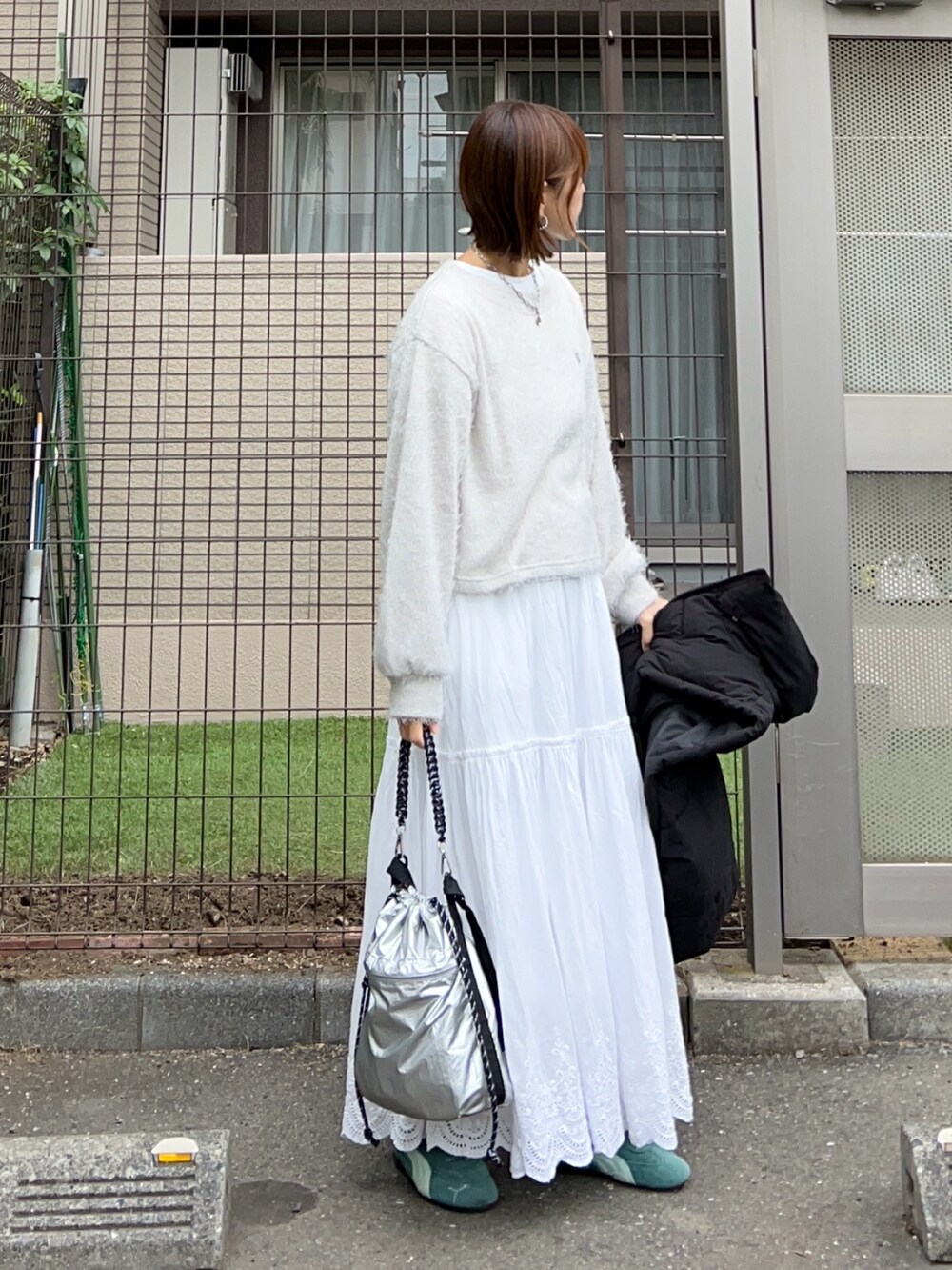 グレー系のニット/セーター、ホワイト系のスカート、シルバー系のショルダーバッグを着用したレディースの秋コーディネートの2枚目の写真